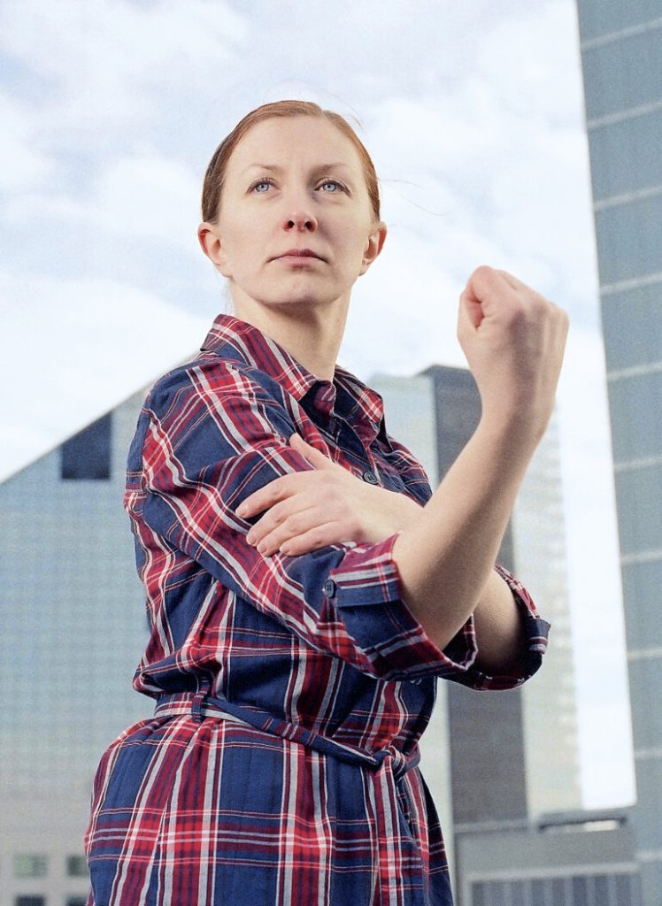 Frau in erhabener Pose vor blauem Himmel.